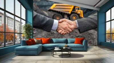 A handshake between two business people in suits, with an open coal mine and large trucks background Wall mural