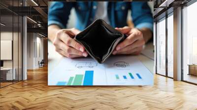 A man is holding a wallet with a hole in it. The wallet is on a table with a calculator and some papers. The man is in a state of distress or frustration Wall mural