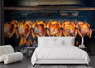 A row of roasted chickens on a grill. The fire is hot and the smoke is rising. The chickens are cooked and ready to be eaten Wall mural