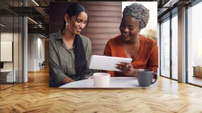 Getting her thoughts. two attractive businesswomen working on a tablet together in their office. Wall mural