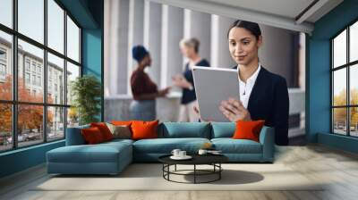 Modern tech making stacks of paperwork something of the past. a young businesswoman using a digital tablet against a city background. Wall mural