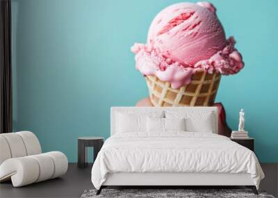 Woman hand holding waffle cone with delicious pink ice cream with blue pastel background Wall mural