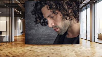 Portrait of desperate young attractive man with curly hair Wall mural