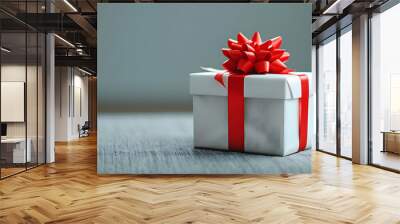 A Close-Up View of a White Gift Box with a Red Ribbon Bow, Sitting on a Gray Fabric Surface, Ready to Be Opened Wall mural