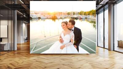 Beautiful wedding couple posing on boat at sea Wall mural