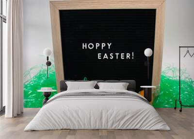 A Black Happy Easter Sign With White Letters, Easter Grass, and Easter Eggs Wall mural