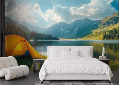 A vibrant orange tent is pitched on the green grass near a tranquil lake on a beautiful summer day Wall mural