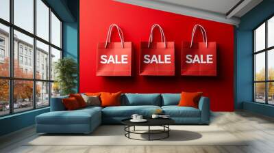 Three red shopping bags with the word sale prominently featured, set against a bold red background, highlighting the thrill of Black Friday deals Wall mural