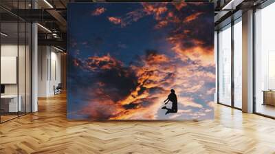 person jumping through the sunset sky. dragon shape cloud background. Wall mural