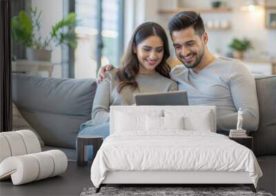 Happy middle aged couple using digital tablet relaxing on couch at home. Smiling mature man and woman holding tab browsing internet on pad device sitting on sofa in living room. Authentic candid photo Wall mural