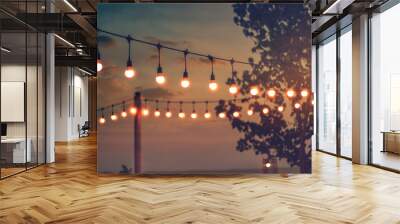 blurred bokeh light on sunset with yellow string lights decor in beach restaurant Wall mural