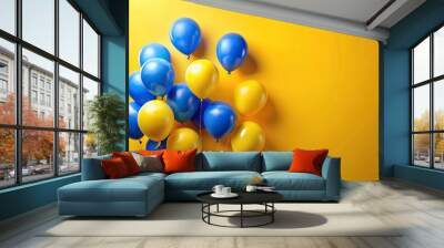 Close-up of blue and yellow balloons floating on yellow background with copy space Wall mural