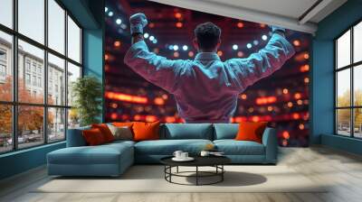 A karate fighter in a white uniform celebrates victory in the ring with arms raised Wall mural