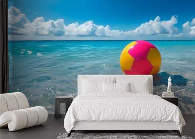 Joyful beach scene with colorful balls splashing in bright blue water beneath a sunny sky filled with fluffy clouds Wall mural