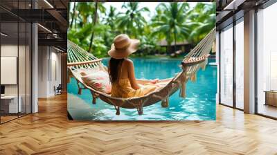 Relaxing woman in hammock above sparkling swimming pool at tropical resort Wall mural