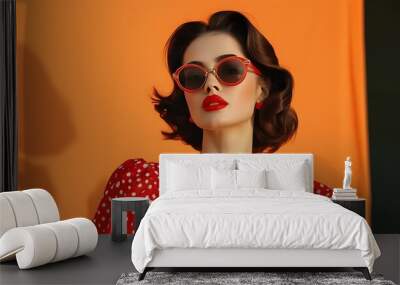 Vintage pin-up girl in red dotted dress and retro sunglasses against bright orange backdrop celebrating Womens Day Wall mural