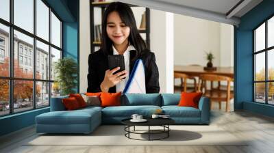 Beautiful young asian business woman in suit standing at cafe with phone and Brown envelope Wall mural