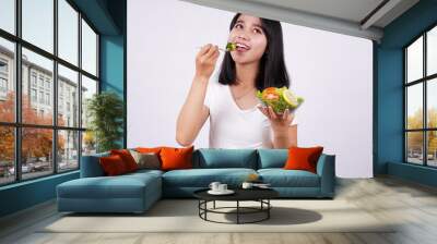 Young asian woman happy eating healthy salad with isolated white background Wall mural