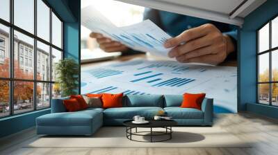 Financial business team presentation with a businessman holding documents containing financial statistics and discussing and analyzing report data charts and graphs Wall mural