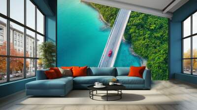 Aerial view of bridge road with red car over blue water lake or sea with island and green woods. Wall mural