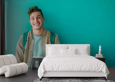 Happy young white male employee standing in front of a turquoise painted wall, dressed in stylish casual attire, showcasing modern workplace fashion and positive attitude. Wall mural