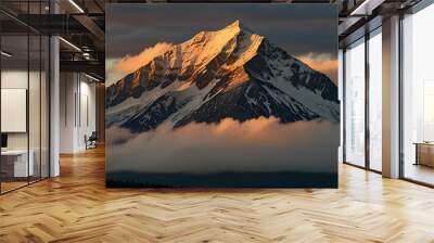 A mountain peak bathed in the soft light of the setting sun, with clouds gathering below. Wallpaper Wall mural