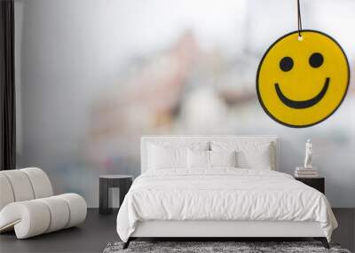 Happy Face Car Air Freshener with large copy space on the left yellow and black smiling face hanging with a blurred white and mixed colour background Wall mural