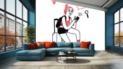 Beautiful young woman tourist sitting on a suitcase Type a message on the phone. Wall mural