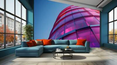 Circular glass tower with reflective magenta panels, highlighted by bright sunlight and clear, vibrant sky Wall mural