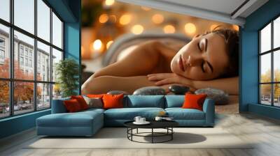 Relaxed young woman with closed eyes enjoying hot stone massage in a tranquil spa setting with candles Wall mural