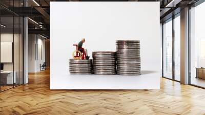 A miniature man in a wheelchair on the coin stack. Wall mural