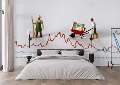 Business concept with graphs and miniature people. A miniature man carrying dollars in the cart on a graph.
 Wall mural