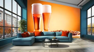 Two glass of beer and pizza over yellow background Wall mural