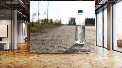 a bottle of water on an empty road Wall mural