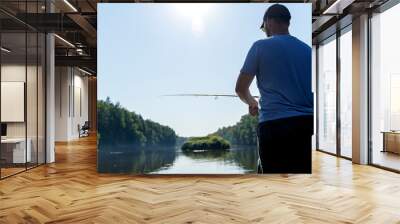 A fisherman is fishing for spinning from a boat Wall mural