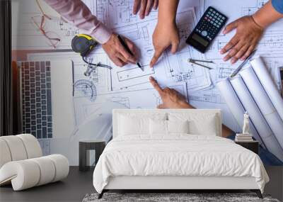 engineers pointing to building on blueprint and using laptop to drawing design building Project in office, construction concept. Engineer concept Wall mural