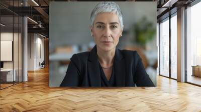 Confident mature woman with short grey hair, professional attire, sitting in office, successful business leader, focused expression, modern workplace, career concept Wall mural