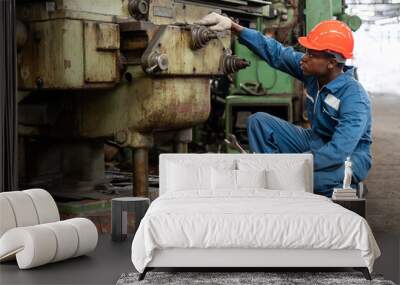 african american Mechanic repairing big heavy industry machine . black engineer maintenance machinery in Large Industrial Factory. young worker checking or inspection working machine at site indoor Wall mural