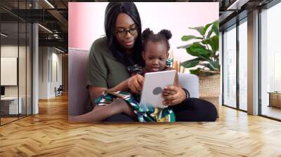 african american mother using tablet with her little daughter on couch at home . black girl lying on her mom learning online at home on sofa together . quarantine Home School Wall mural