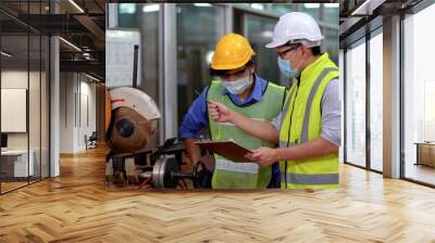 asian Engineer manager wearing protective face mask holding clipboard training mechanic worker operating machine industrial in industry manufacturing factory . during Coronavirus or Covid 19 pandemic Wall mural