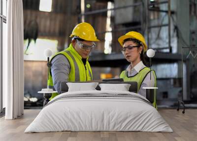 asian industrial Engineer manager man wearing eyeglass and helmet   discussion with mechanic worker woman while using digital tablet checking industry manufacturing large factory . inspection Wall mural