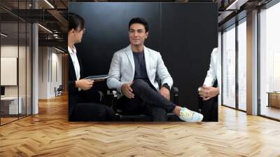 asian master of ceremonies or journalist in suit giving interview to business man and woman to success or couple celebrity to love life in black studio tv show or on air online Wall mural