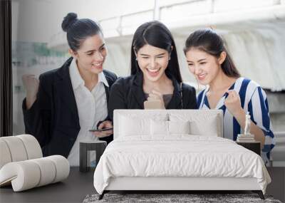 group of beautiful young women friends  using a smart phone and laughing outdoors .three girl exciting business online of news Wall mural