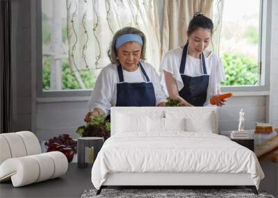 happy asian young daughter and senior mother cooking online  class on tablet together making fresh vegetables food in kitchen at home Wall mural