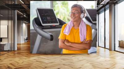 Senior older man taking a break from workout listening music with headphones relaxing in fitness gym. aged . Old male .Mature sport training.rehabilitation.elderly Healthy lifestyle Wall mural