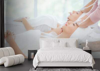 two beautiful young woman enjoying face massage relaxing in beauty spa salon Wall mural