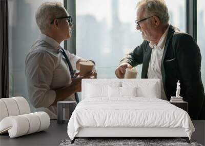 two senior businessman take a break drinking coffee and discussing business strategy in coffee shop at modern restaurant on a tall building cityscape background . old friend talking or life advice Wall mural