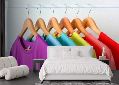 close up collection of colorful rainbow t-shirts hanging on wooden clothes hanger in closet or clothing rack over white background Wall mural