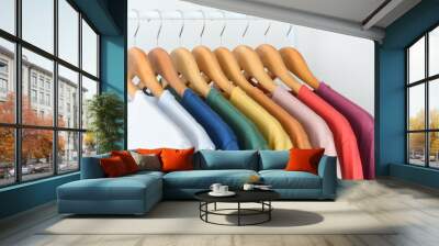 close up collection of colorful t-shirts hanging on wooden clothes hanger in closet or clothing rack over white background, copy space Wall mural