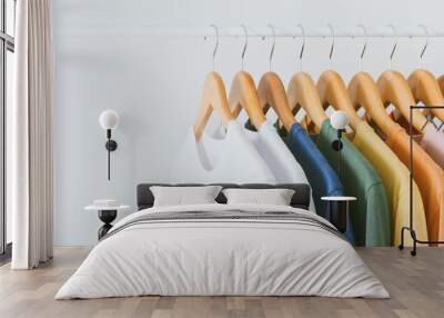 close up collection of colorful t-shirts hanging on wooden clothes hanger in closet or clothing rack Wall mural